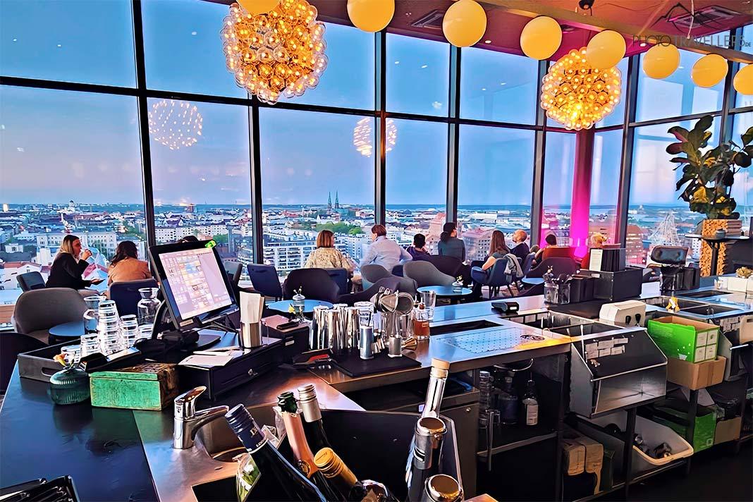 Les invités dans le Sky Room regardent vers le bas sur Helsinki depuis le bar sur le toit en verre.