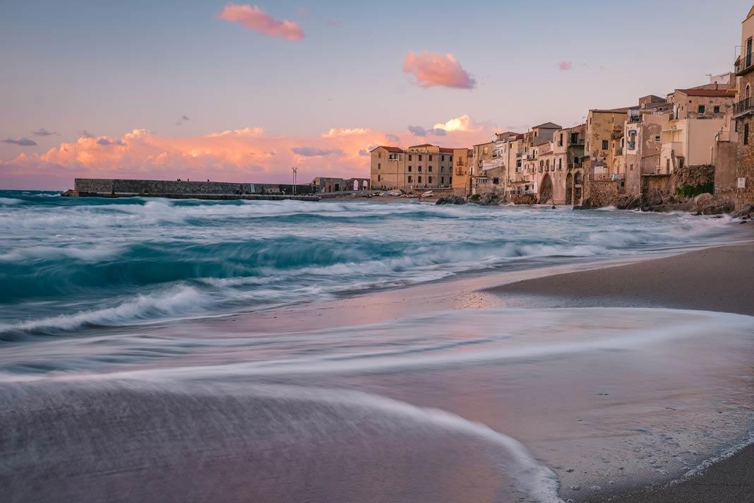 A praia de Cefalù com as casas da vila ao entardecer