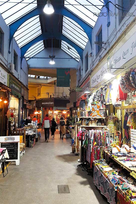 Des visiteurs flânent entre les stands décorés de couleurs dans le marché couvert de Brixton