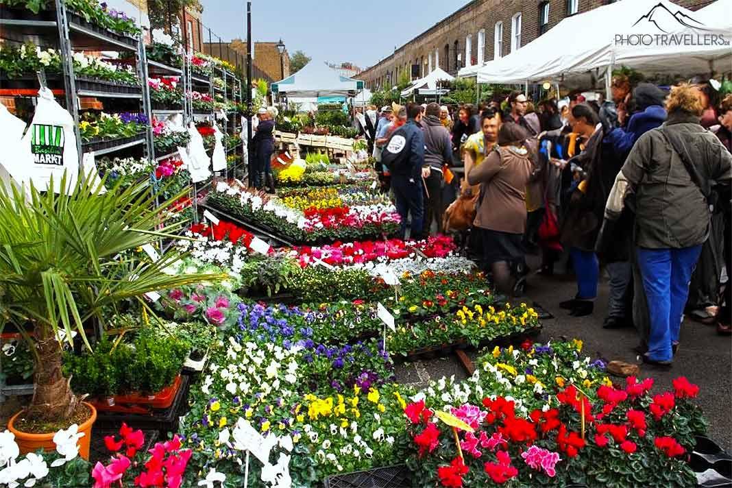 De nombreuses personnes flânent le long des stands colorés du Portobello Road Flower Market