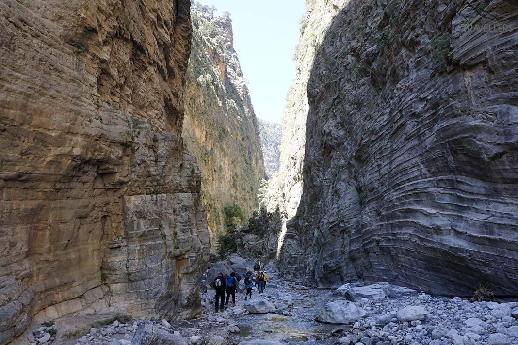Un plus grand groupe de randonneurs entre de hautes falaises dans la gorge de Samaria