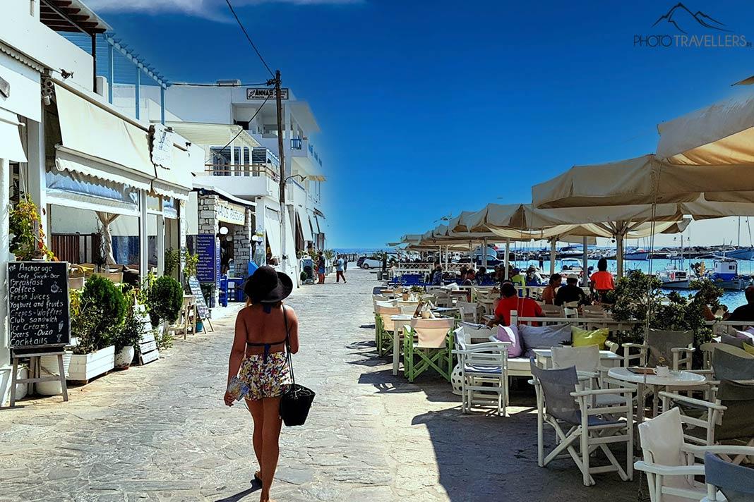 Una mujer con sombrero y falda pasea por la promenade del puerto de Aliki