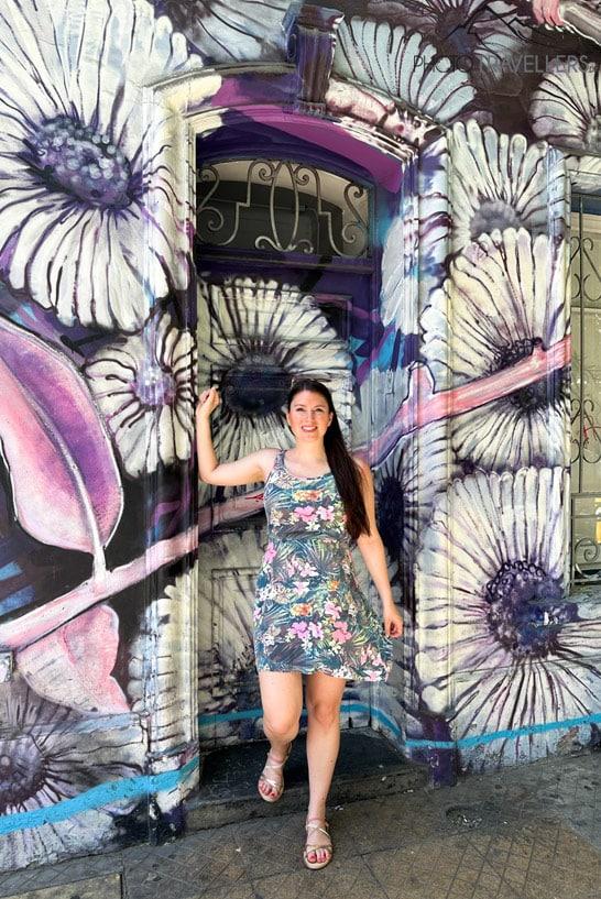 A blogueira de viagens Biggi Bauer em vestido de verão diante de um grafite colorido no Barrio Bellavista