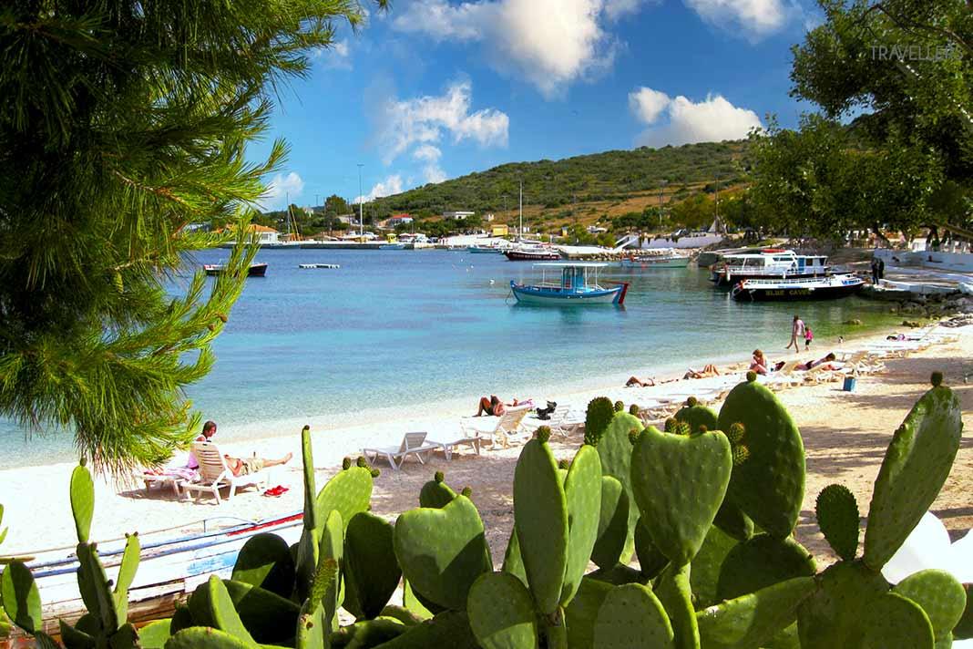 Des baigneurs et des petits bateaux longent la plage recouverte de cactus à Agios Nikolaos