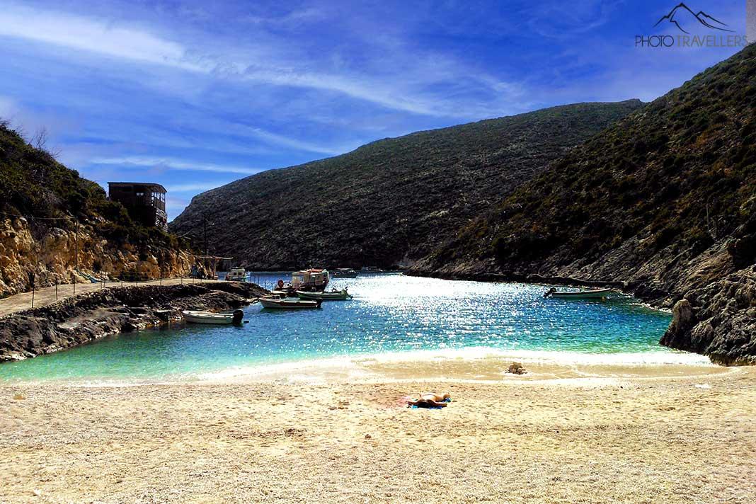 Eau turquoise et sable doré devant le rocher verdoyant à Porto Vromi