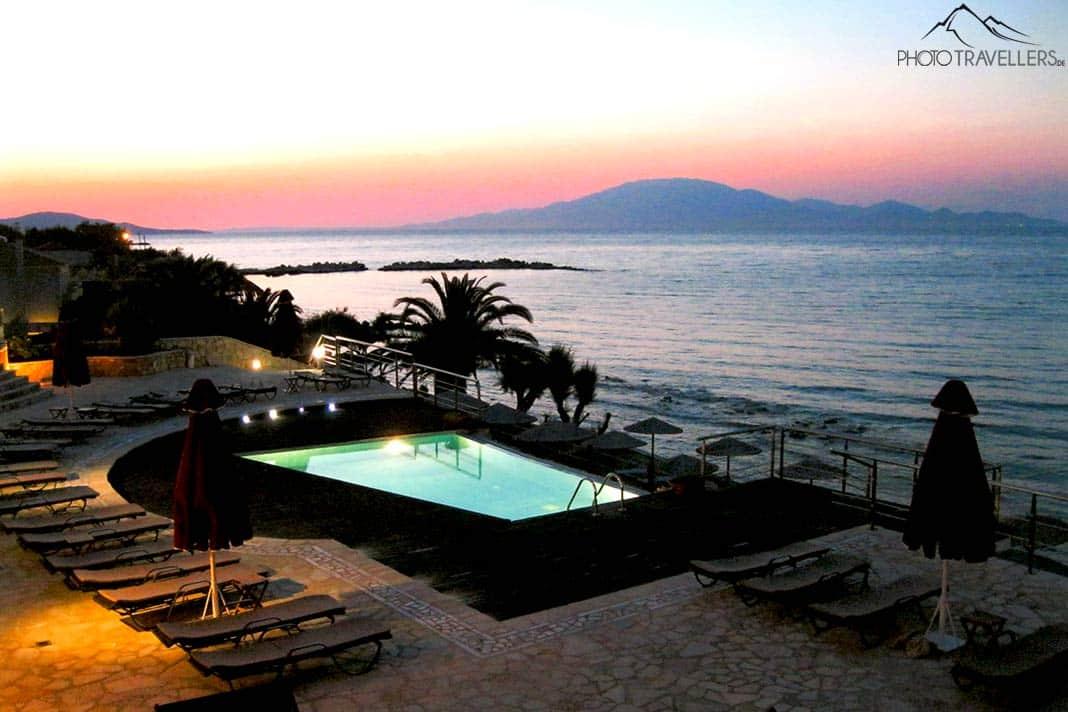 Piscine d'hôtel éclairée au coucher du soleil avec la mer en arrière-plan