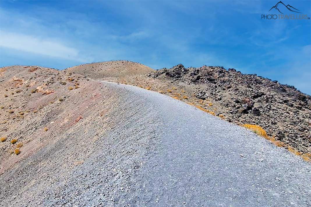 Un sentier étroit et clair en pierre traverse le paysage volcanique de Nea Kameni