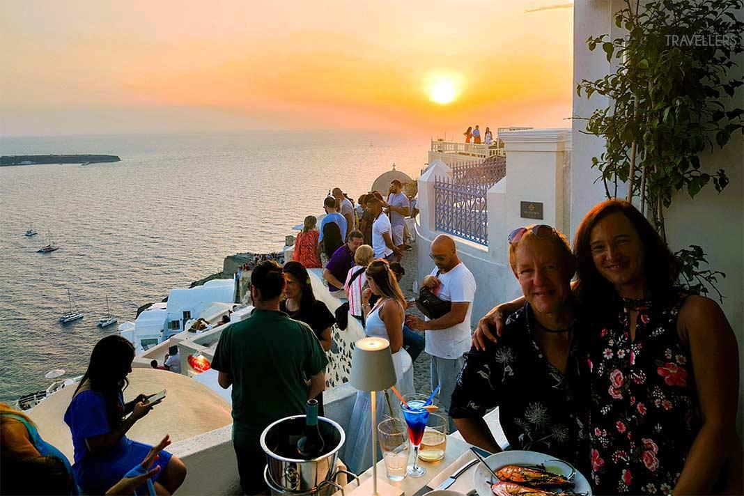 Des invités s'installent à table au coucher du soleil dans une taverne à Oia