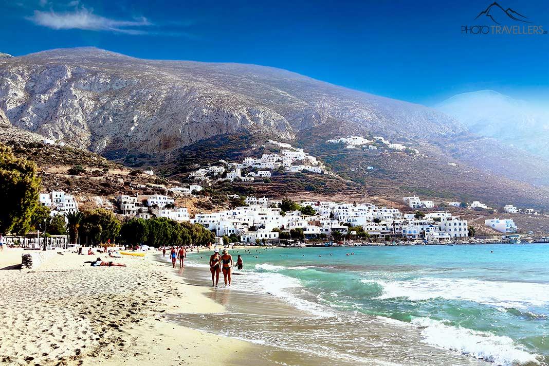 Des baigneurs marchent sur le sable dans la baie d'Aegiali entourée de montagnes