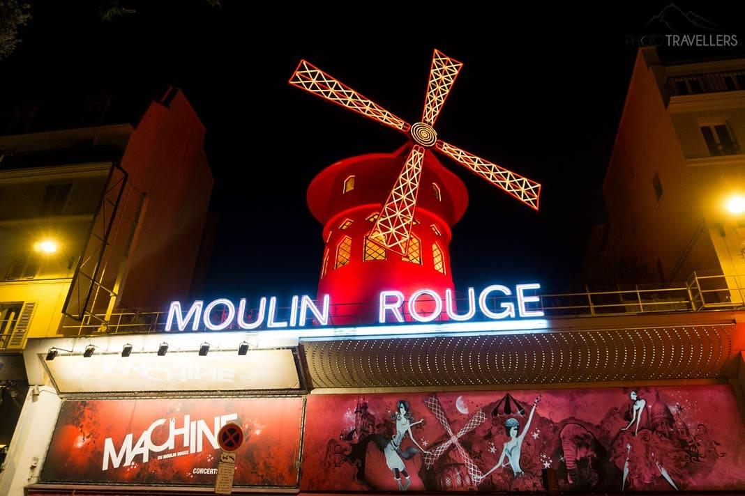 A famosa fachada do Moulin Rouge com a roda giratória iluminada em vermelho em Paris