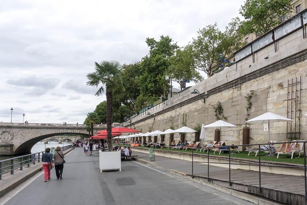 Caminhantes na calçada à beira do Sena em Paris