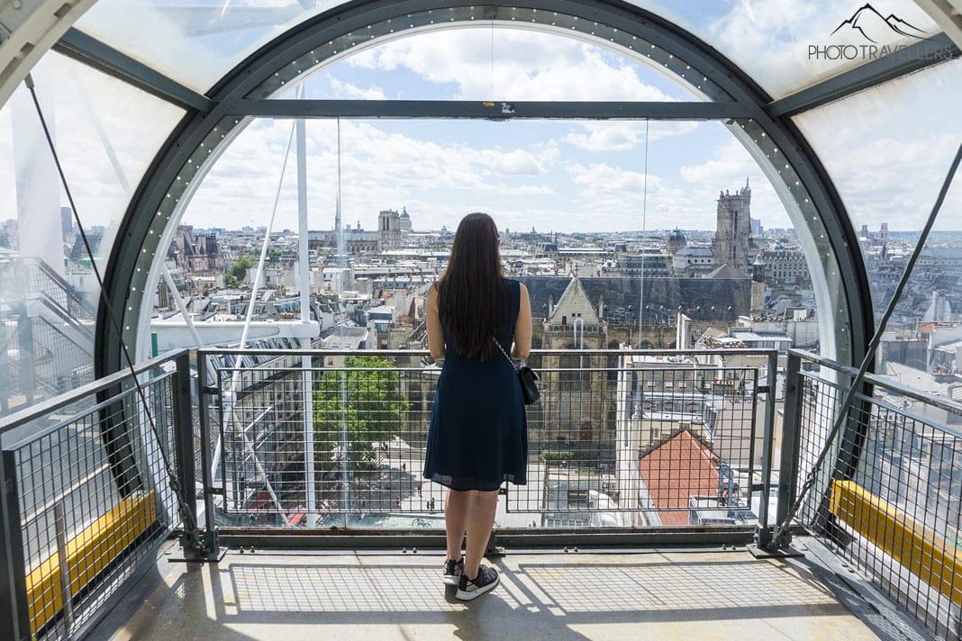 Blogueira de viagens Biggi Bauer olhando através de uma grande janela no Centre Pompidou para Paris