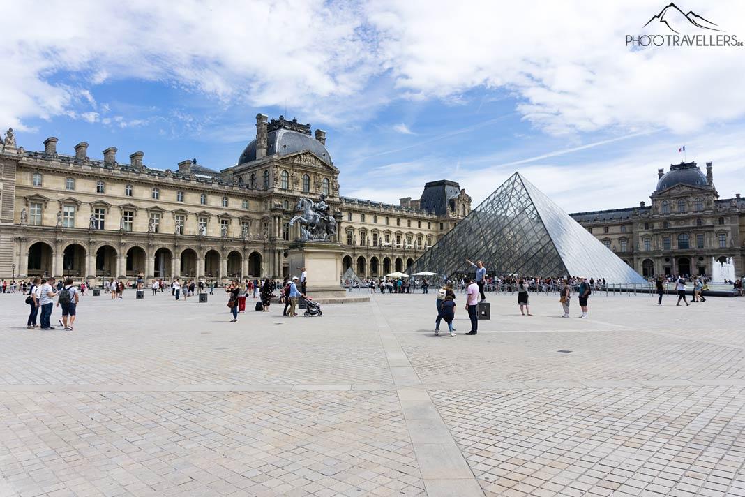 Pessoas diante da pirâmide de vidro do Louvre