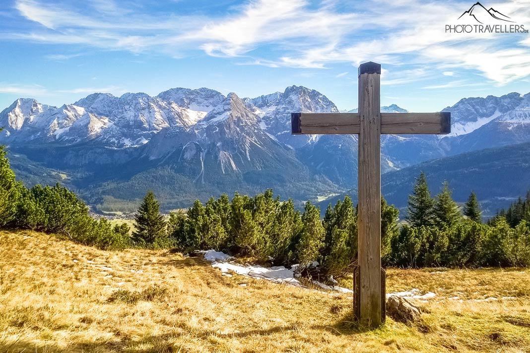 Um marco de madeira no caminho Alpenrosen, ao fundo a Ehrwalder Sonnenspitze