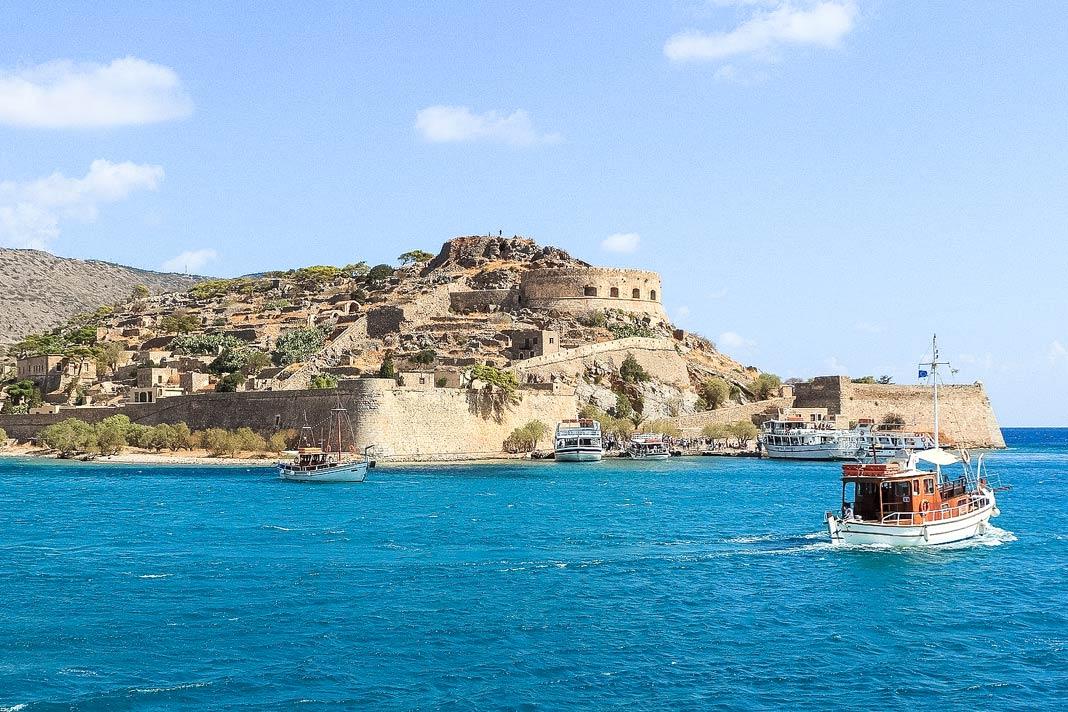 Vue sur l'île de Spinalonga avec l'ancienne station de lèpre, quelques bateaux devant