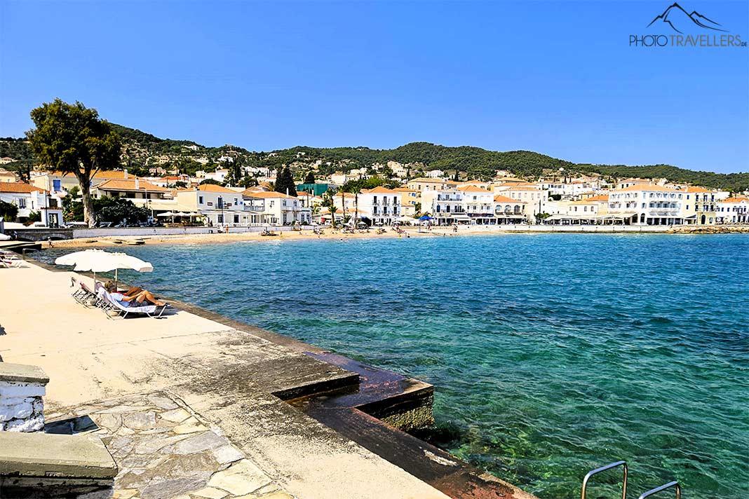Sur la plage de la ville de Spetses, des gens sont allongés dans le sable et sur des terrasses