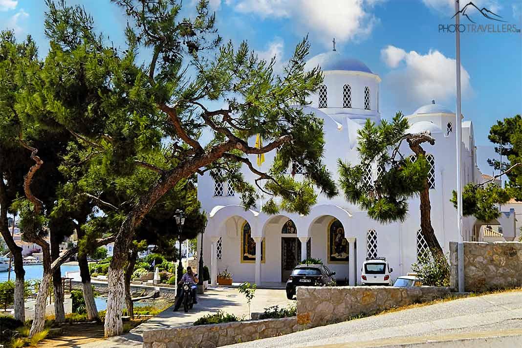 L'église blanche Agios Nikolaos se distingue par son dôme bleu et des arbres dans le jardin