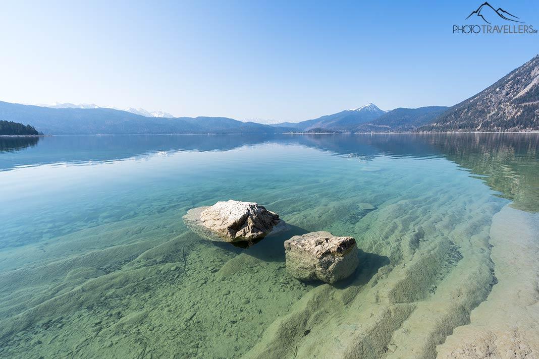 Dos rocas en el agua clara del Walchensee, con las montañas al fondo