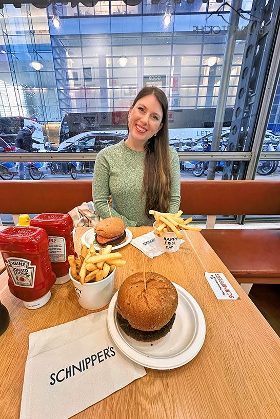 Le blogueur de voyage Biggi Bauer à table avec deux burgers et des frites chez Schnippers à New York