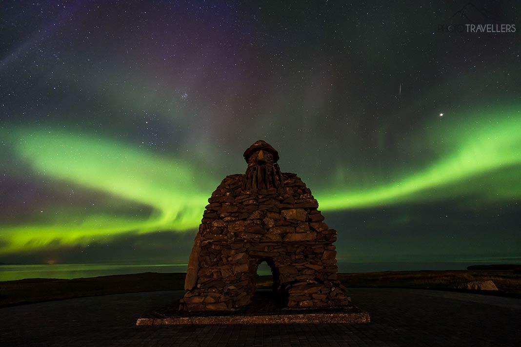 Le troll de pierre sur la côte d'Arnarstapi en Islande avec des aurores boréales