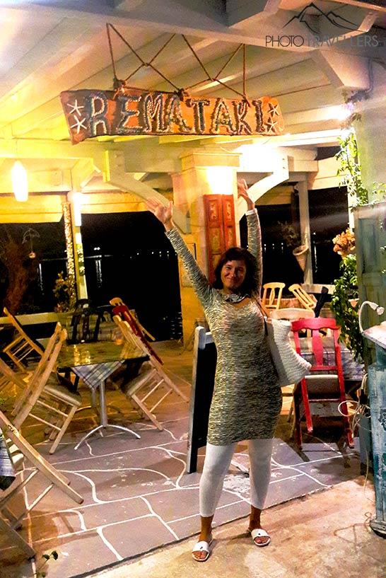 Uma mulher levanta os braços e sorri diante de uma taverna vazia