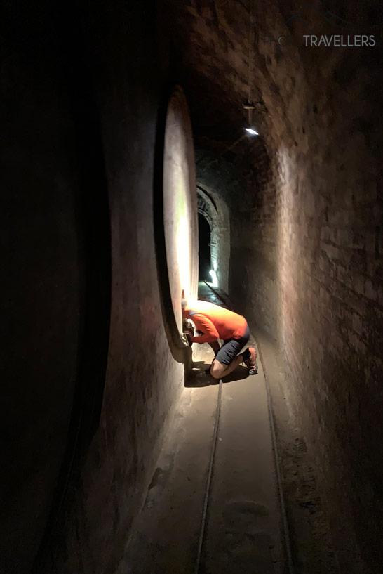 Une personne regarde à l'intérieur d'un grand fût à vin lors de la visite des caves d'expérience à Retz