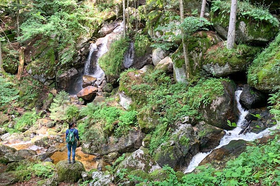 La bloguera de viajes Biggi Bauer frente a una cascada en la Ysperklamm