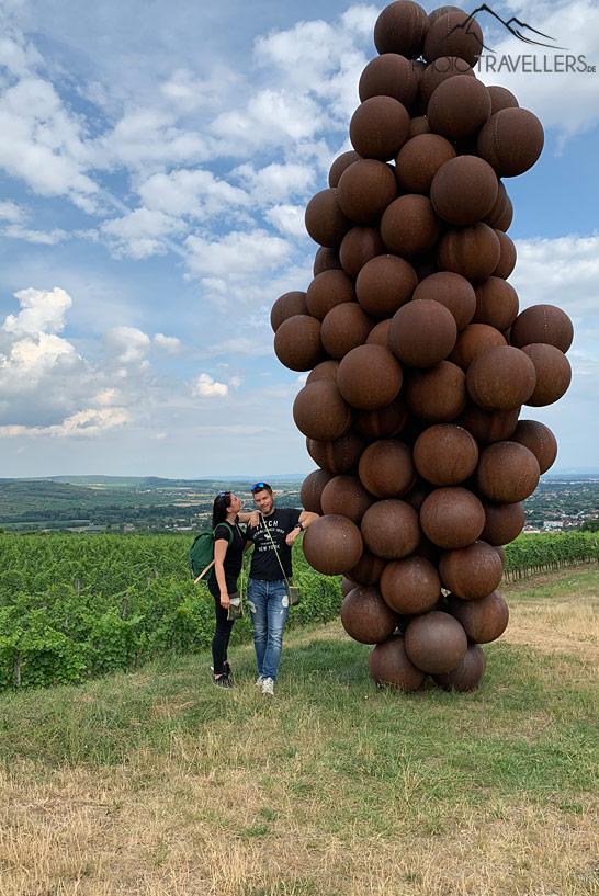 Los periodistas de viajes Biggi Bauer y Florian Westermann frente a una gigantesca escultura de uva en el Camino del Vino Langenlois