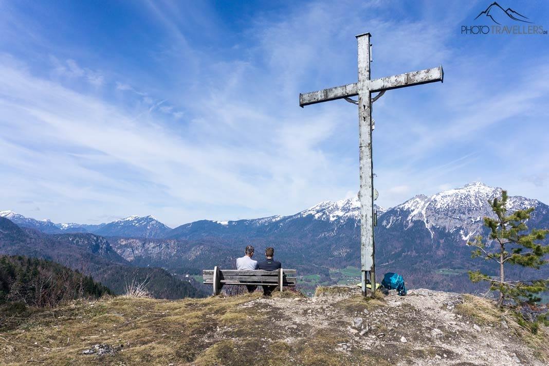Deux randonneurs de dos sur un banc au Dötzenkopf, à côté de la croix du sommet