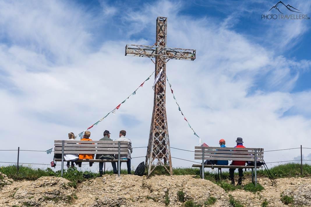 La croix du sommet du Hochgrat. À côté deux bancs avec des randonneurs regardant au loin