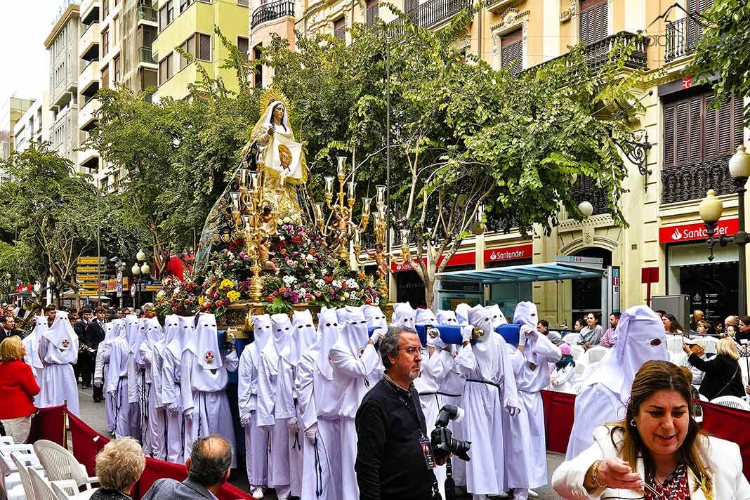 Des participants d'une procession vêtus de voiles blanches portent un autel