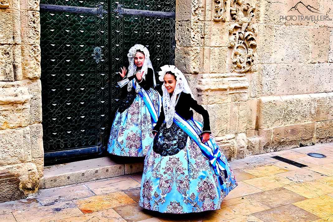 Deux filles en costumes historiques bleu et noir se tiennent devant une porte verte