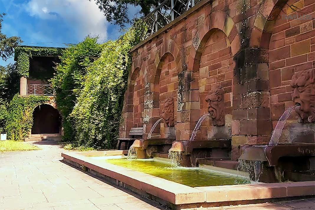 Três gárgulas se projetam da parede de pedra vermelha da Terraça St.-Germain