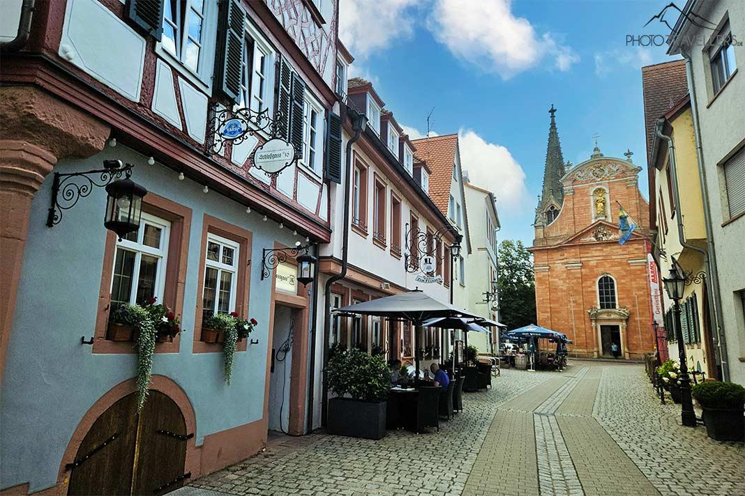 Hospedarias e uma igreja se alinham na pavimentada Rua do Castelo