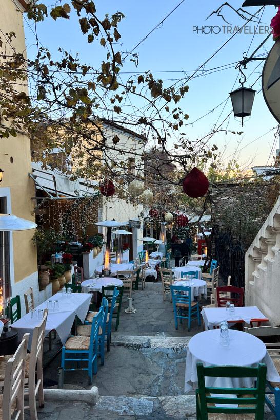 Mesas y sillas de los restaurantes en el callejón Mnisikleous en el barrio de Plaka en Atenas