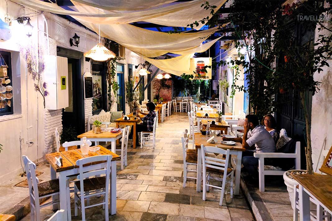 Em uma taverna de uma rua tranquila, poucas pessoas se sentam nas mesas e cadeiras