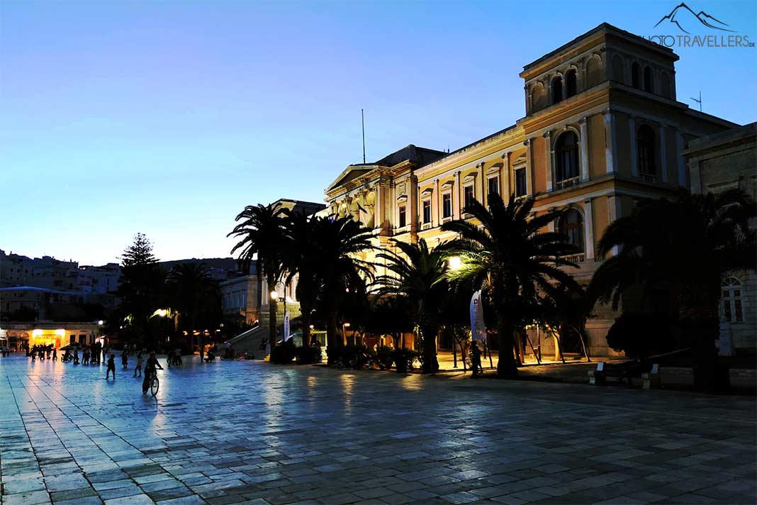 La placette pavée de Miaouli avec le bâtiment administratif illuminé au crépuscule