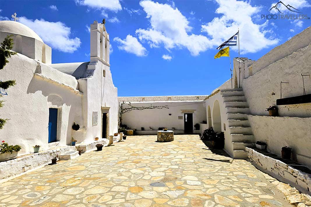 La fachada blanca y un muro exterior con escaleras enmarcan el patio adoquinado del monasterio Zoodochos Pigi