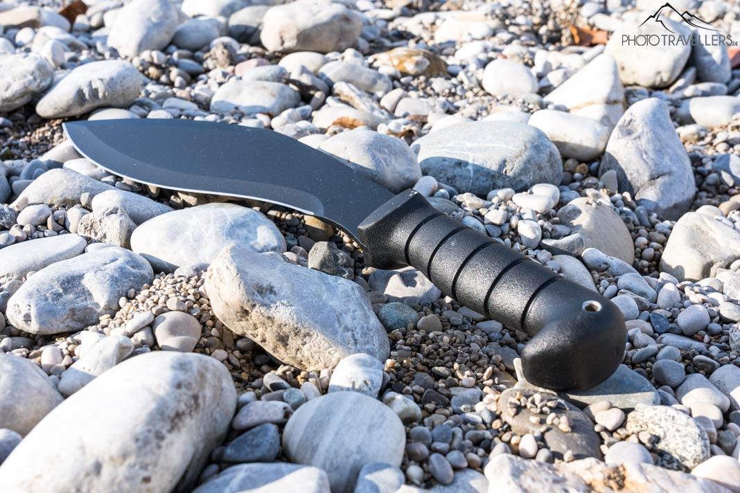 Um Kukri com cabo preto entre pedras