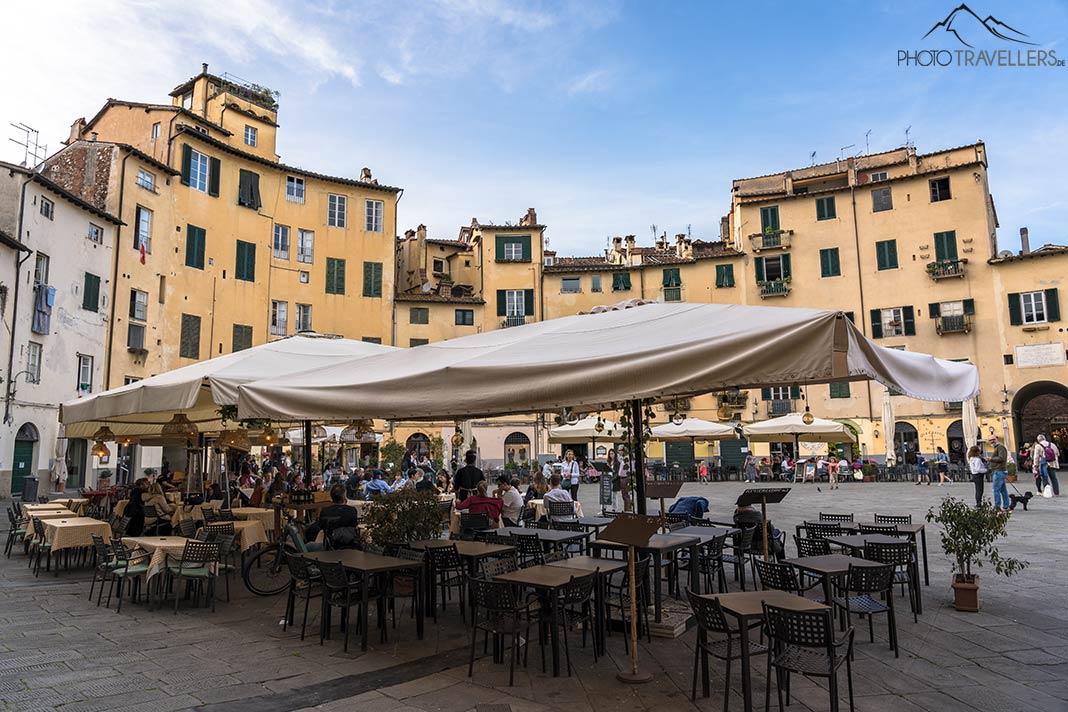 Mesas e cadeiras de um restaurante na Piazza dell'Anfiteatro em Lucca
