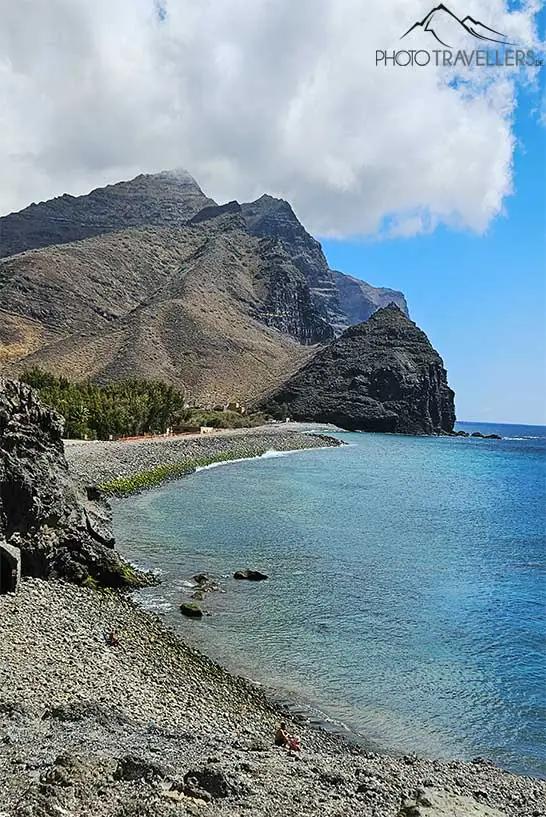 Une puissante chaîne de montagnes de roche volcanique s'élève derrière la baigneuse baie d'Aldea