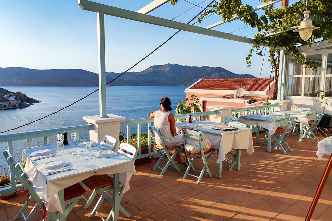Une femme est assise à une table en terrasse surplombant la mer