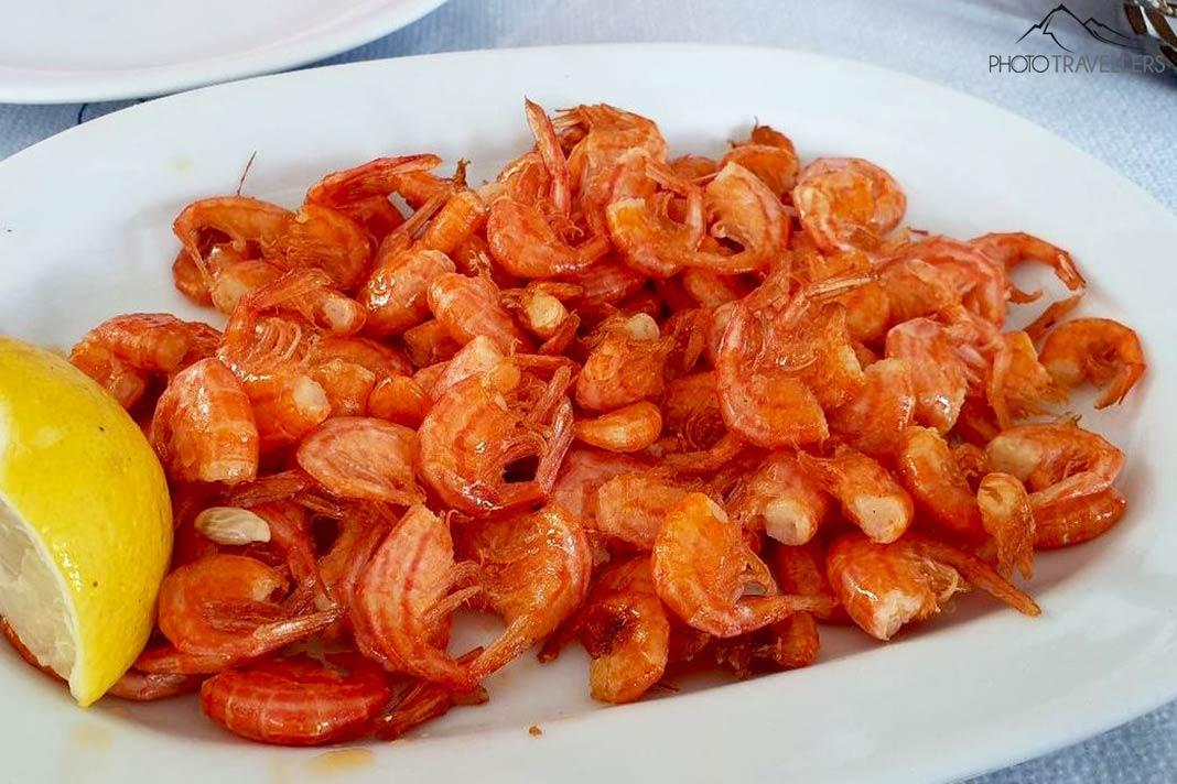 De nombreuses petites crevettes orange décorent une assiette avec du citron