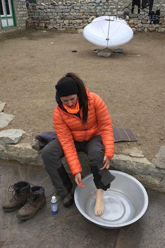 La journaliste de voyage Biggi Bauer lave ses pieds dehors dans une bassine dans un lodge au Népal