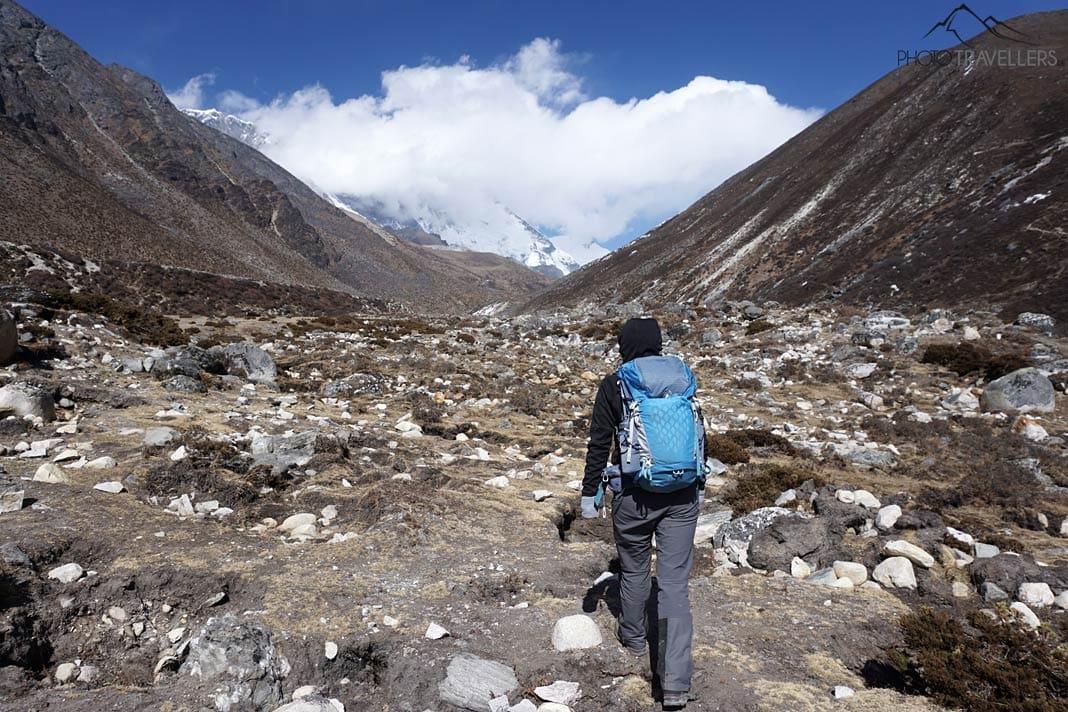 La blogueuse de voyage Biggi Bauer marche entre de hautes montagnes au Népal avec un sac à dos Gregory Maven bleu