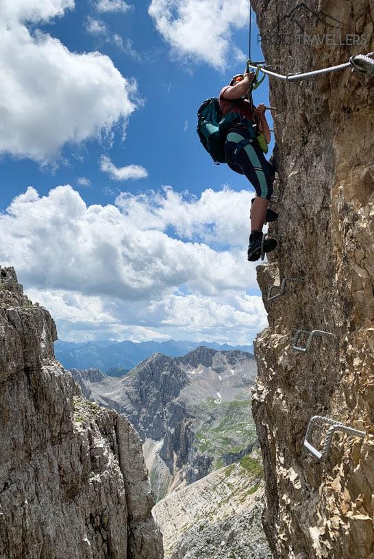 La bloguera de viajes Biggi Bauer en escalones de una pared de roca en el klettersteig Latemartürme