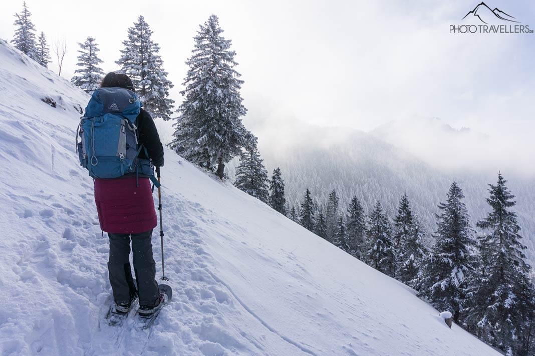 La blogueuse voyageuse Biggi Bauer avec un sac à dos et des raquettes dans la neige