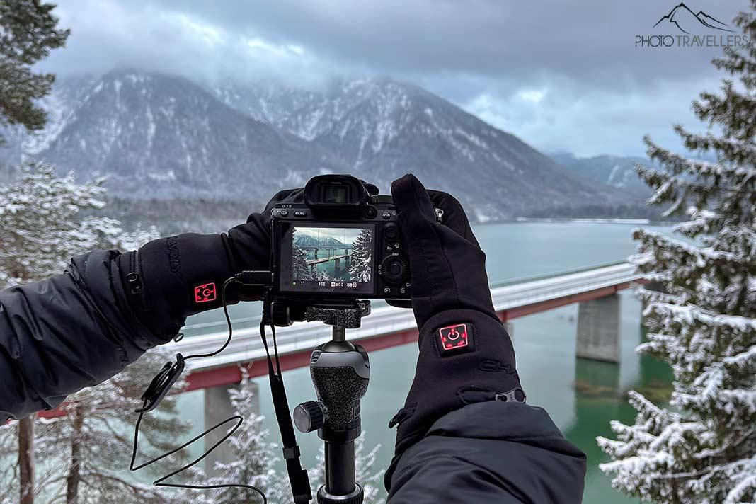 Gants chauffants Charly Fire Basic utilisés sur une caméra avec vue sur un lac de montagne en hiver