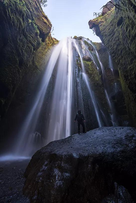 Le blogueur voyage Florian Westermann devant la cascade Gljúfrabúi en Islande dans une grotte