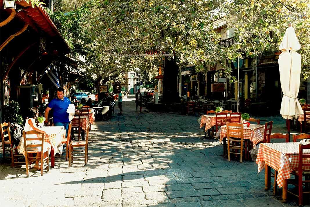 Des clients sont assis aux tables d'une taverne sous des platanes à Agiasos